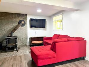 a living room with a red couch and a fireplace at Waterfront with Spa - Le Retro in Windsor