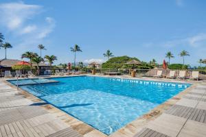 a pool at a resort with chairs and palm trees at Eldorado L202 · EL L202 Updated Condo with Beachfront Cabana in Kahana