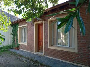 a brick house with a brown door and windows at Casa Las Marías in General Belgrano