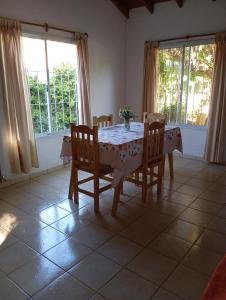 ein Esszimmer mit Tisch und Stühlen und zwei Fenstern in der Unterkunft Casa Las Marías in General Belgrano + 5 Fotos