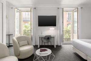 ein weißes Wohnzimmer mit einem Bett und einem Fernseher in der Unterkunft Room Mate Mario, Madrid in Madrid