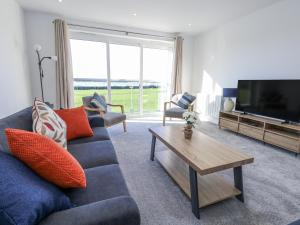 a living room with a blue couch and a tv at Sea Fern House - 36B in Poole