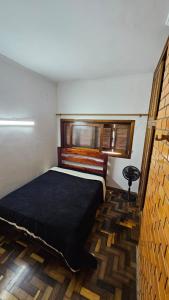 ein Schlafzimmer mit einem Bett in einem Zimmer mit Fenster in der Unterkunft Apartamento de 1 quarto próximo a praia - Com Estacionamento Rotativo in Tramandaí