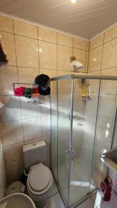 ein Badezimmer mit Toilette und Glasdusche in der Unterkunft Apartamento de 1 quarto próximo a praia - Com Estacionamento Rotativo in Tramandaí