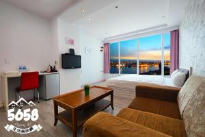 ein Zimmer mit einem Bett, einer Couch und einem Tisch in der Unterkunft 85高雄港商旅 in Ta-lin-wei