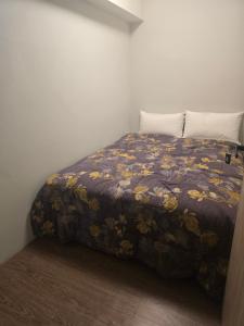 a bedroom with a bed with a floral blanket at Hao Chi Tao Hotel in Kaohsiung