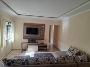 uma sala de estar com um sofá e uma TV de tela plana em Casa Feliz em Cascavel