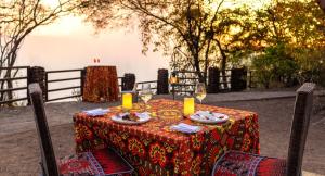 a table with a plate of food and a glass of wine at Raydia Ventures Travel and Tours in Livingstone