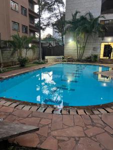 Cozy Two-Bed Retreat في نيروبي: مسبح ازرق كبير في مبنى