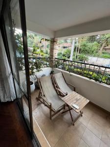 Cozy Two-Bed Retreat في نيروبي: كرسي هزاز على شرفة مطلة