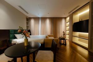 a hotel room with a bed and a table and a couch at TQ Luxury Hotel & Apartment in An Khê