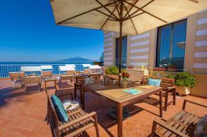 ソレントにあるDe Luxe La Terrazzaのテーブルと椅子と傘のあるパティオ +36枚の写真