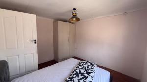 a bedroom with a white bed with a black and white blanket at Maun HideOut in Maun Airport