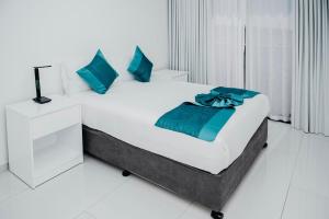 Un dormitorio blanco con una cama grande con almohadas azules. en Golf View Apartment-AP4, en Maputo