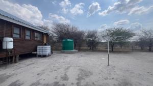 a tree in the dirt next to a house at Maun HideOut in Maun Airport