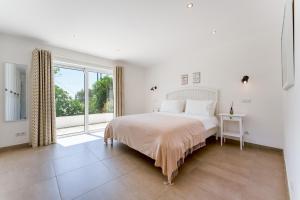 una camera bianca con un letto e una grande finestra di Villa Benjamin - Vale do Lobo a Vale do Lobo Altre 79 foto