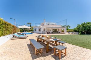 un patio con tavolo, sedie e una casa di Villa Benjamin - Vale do Lobo a Vale do Lobo