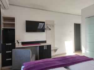 um quarto com uma TV na parede e um cobertor roxo em Darázshegyi Panzió gluténmentes félpanzióval is em Mátraszentimre