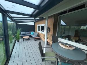 a deck with a table and chairs and a couch at Strandnahes Ferienhaus NR 2 mit Wintergarten grosser uneinsehbarer Garten in Sint Maartensvlotbrug
