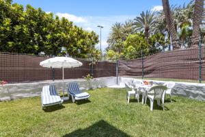 un tavolo con sedie e un ombrellone sull'erba di Apartamento FORESTA 6 a San Bartolomé