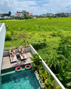 two people sitting on a deck in a swimming pool at Cemagi Beach Hostel by Verdana Pool & Events in Cemagi