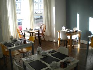 una sala da pranzo con tavoli e sedie e una finestra di Morlea Guest House a Llandudno