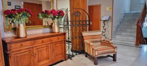 a room with a dresser with flowers and a chair at Hotel Real De Toledo in Toledo