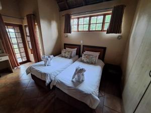 Unit 77 Kubu Mabalingwe nature reserve في وارمباثس: سريرين توأم في غرفة مع نوافذ