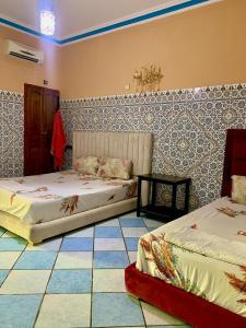 Un dormitorio con dos camas y suelo de baldosas. en Hotel Complex Europe, en Guercif