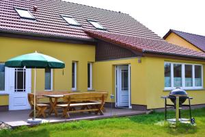 una casa gialla con un tavolo e un ombrellone verde di Port007 a Priepert