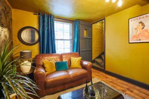 a living room with a brown leather couch and yellow walls at Host & Stay - The Little Townhouse in Southwell +15 photos