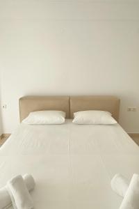 a large white bed with two pillows on it at Pnoe Home in Kavála