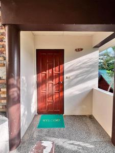 uma porta vermelha com um sinal de boas-vindas em frente em Sense Asia em Haad Tian