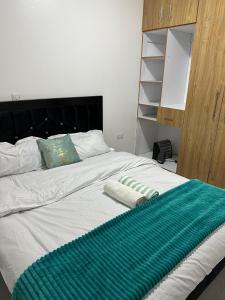 a bed with a green and white blanket on it at Galaxy Suites Meru in Meru