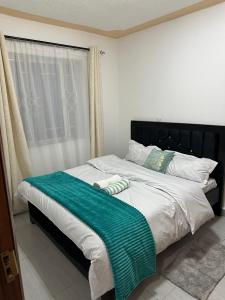 a bed with a green blanket on it in a bedroom at Galaxy Suites Meru in Meru