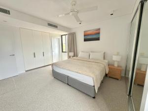 a white bedroom with a bed and a window at The Palms at Waterfront in Darwin