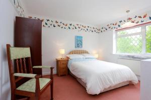 a bedroom with a bed and a chair and a window at Bournemouth Holiday Home in Southbourne