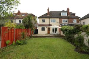 ein Haus mit einem roten Zaun und einem Hof in der Unterkunft Bournemouth Holiday Home in Southbourne
