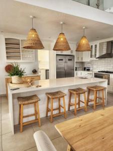 a kitchen with wooden stools and a white counter top at White Wicker House in Langebaan