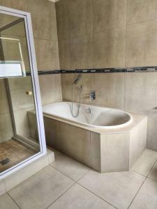 a bathroom with a bath tub next to a shower at White Wicker House in Langebaan +17 photos