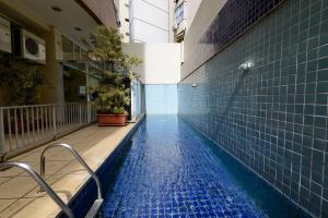 a swimming pool in a building with blue tiles at Flat c/ Limpeza Diária e Estacionamento - LB507 in Rio de Janeiro