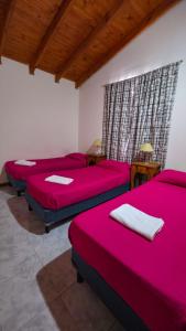 um quarto com 4 camas com lençóis vermelhos e uma janela em Apartamentos Matices em El Calafate