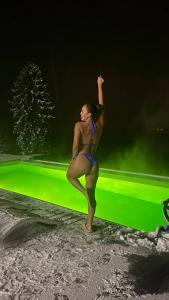 a woman in a bikini standing on a beach with her arm in the air at Rest Hub in Slavske