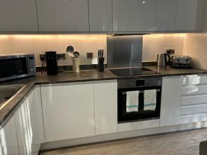 Una cocina con gabinetes blancos y un horno de estufa. en Cozy Studio in Solihull with Parking - NEC or Airport, en Solihull 19 fotos más