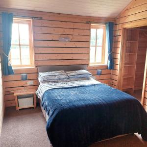 Deer Cabin-hot tub-dog friendly-mountain view في Llanbrynmair: غرفة نوم مع سرير في كابينة خشبية
