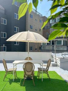 a table and chairs with an umbrella on a lawn at 부산 광안리 B&B stay in Busan