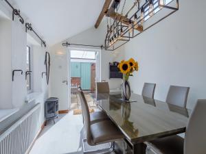 a dining room table with chairs and a vase with a sunflower at Ravensmere Villa in Beccles