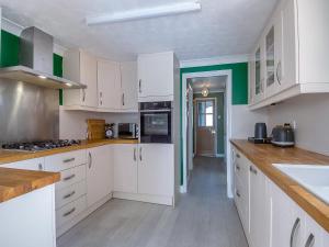 a kitchen with white cabinets and green walls at Ravensmere Villa in Beccles