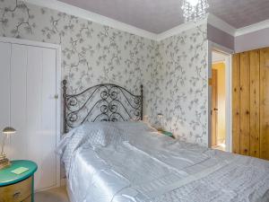 a bedroom with a large bed with floral wallpaper at Ravensmere Villa in Beccles +16 photos