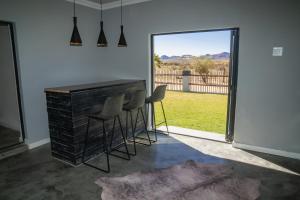 斯普林博克Kénosis Guest Farm Main House的一间有桌子、椅子和大窗户的房间